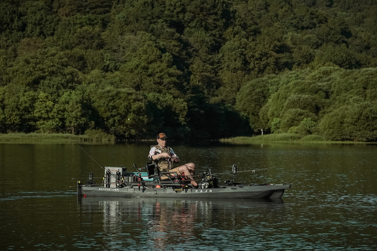 An angler pedalling a CAJO Outpost 128 across a still lake